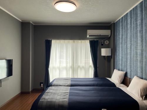 a bedroom with a large bed and a window at Stay Airport in Fukuoka
