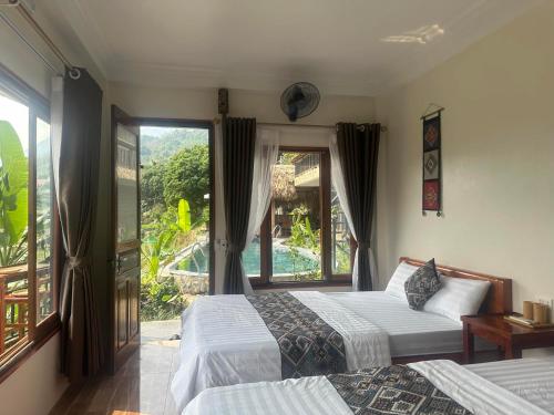 a bedroom with two beds and a large window at Peaceful MaiChau Homestay in Mai Chau