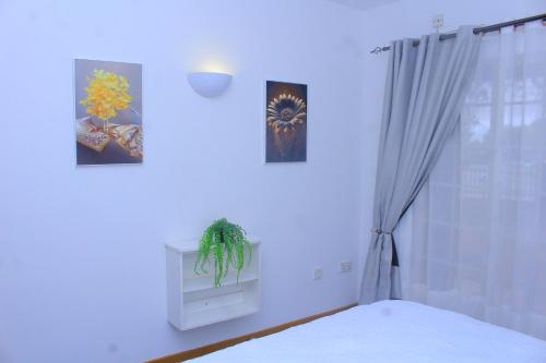 a bedroom with a bed and two pictures on the wall at Cozy stay in Gaborone