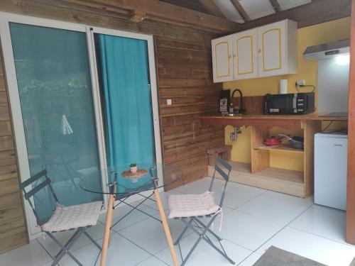 eine kleine Küche mit einem Glastisch und 2 Stühlen in der Unterkunft GWADA FUN HABITATION in Saint-Claude