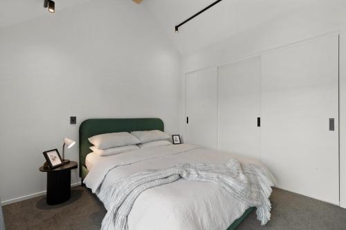 ein weißes Schlafzimmer mit einem Bett mit einer Decke darauf in der Unterkunft Woolshed retreat - Queenstown in Queenstown