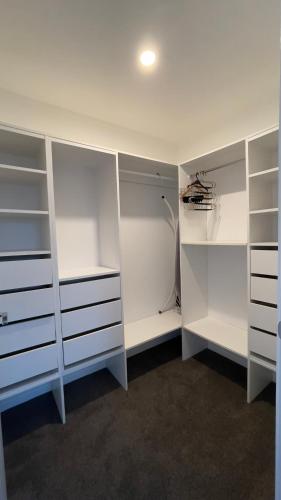 a white walk in closet with white shelves at Quiet and private room for stay in Wellington