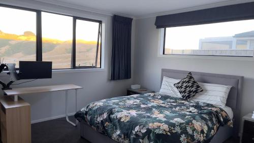a bedroom with a bed and a desk and two windows at Quiet and private room for stay in Wellington