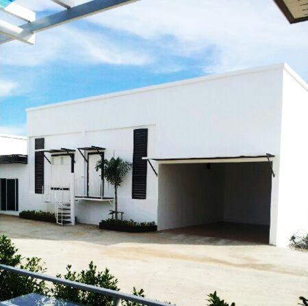 a white building with a garage in front of it at The Vista Pool Villa in Kanchanaburi