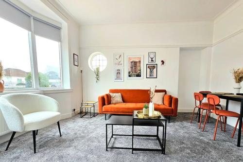 ein Wohnzimmer mit einem orangenen Sofa und einem Tisch in der Unterkunft Charming 3-Bed Oasis-free parking in Glasgow