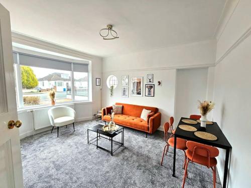 a living room with an orange couch and a table at Charming 3-Bed Oasis-free parking in Glasgow