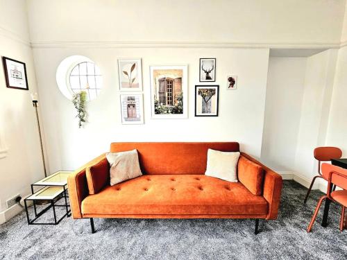 eine orangefarbene Couch im Wohnzimmer in der Unterkunft Charming 3-Bed Oasis-free parking in Glasgow