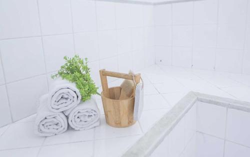 a white tiled bathroom with a potted plant and towels at Multiparque Sudoeste Dária Brasil 65659 in Brasília
