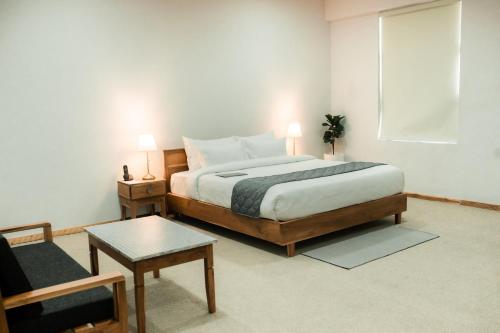 ディマプルにあるTHE HIMBS HOTELのベッドルーム1室(ベッド1台、椅子、テーブル付)