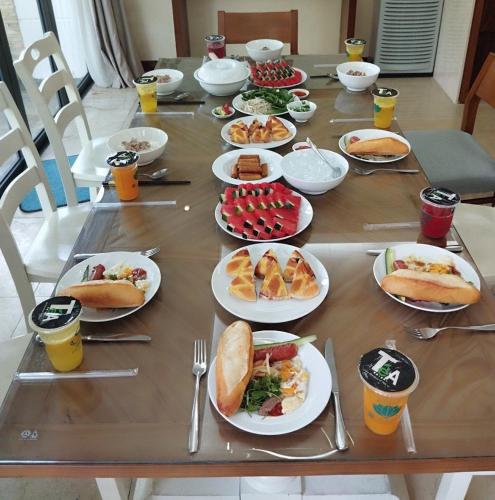 een lange tafel met borden eten en drinken bij Da Nang Beach Villa Resort in Da Nang