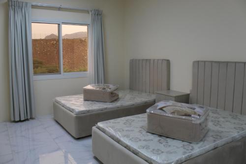 three beds in a room with a window at Hatta Hills in Al Ḩajarayn