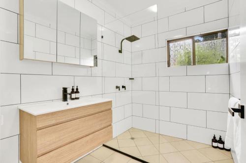 een badkamer met een wastafel en witte betegelde muren bij Comino on Connemara in Trinity Beach