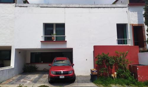 un coche rojo estacionado frente a un edificio blanco en Casa Paseos del Sol en Las Cardenas