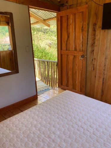 um quarto com uma cama e uma porta de madeira em Mario´s Lodge Providencia em El Copey