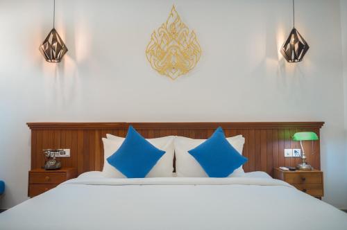 a bedroom with a large bed with blue pillows at Angkor Aurora in Siem Reap