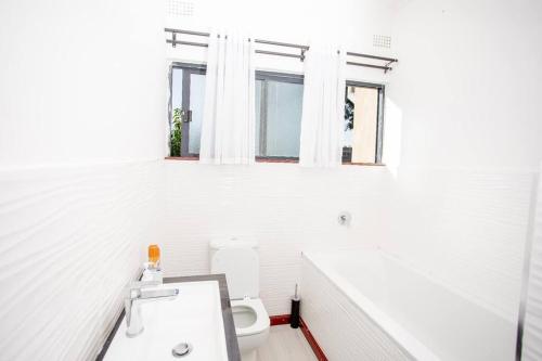a white bathroom with a toilet and a sink at T&T Apartment in Ndola