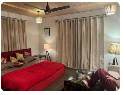 a bedroom with a red bed and a person sitting on a couch at Home stay kashmir in Srinagar