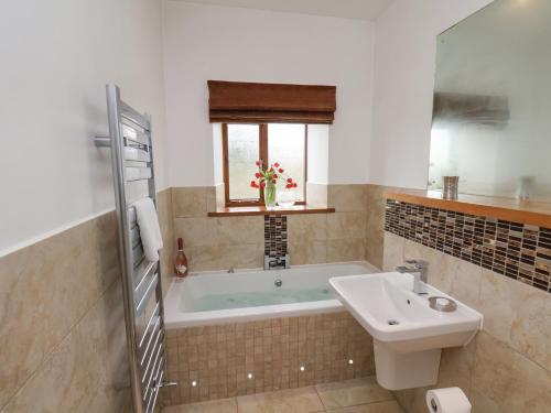 a bathroom with a bath tub and a sink at Dairy Cottage in Staintondale