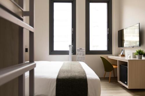 a bedroom with a bed and a desk and two windows at Meander 1948 in Taipei