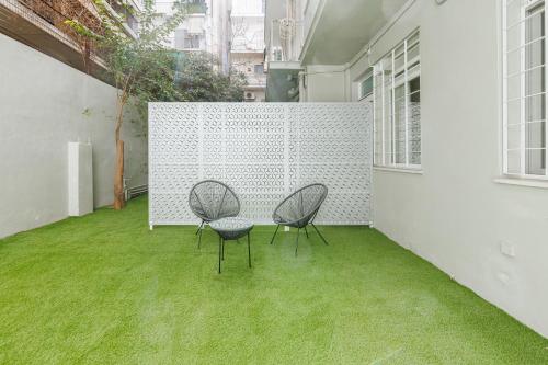 Snug studio apartment with pvt garden access I في أثينا: كرسيين وطاولة على فناء مع عشب