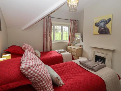 a bedroom with two red beds and a fireplace at Glenside in Far Sawrey