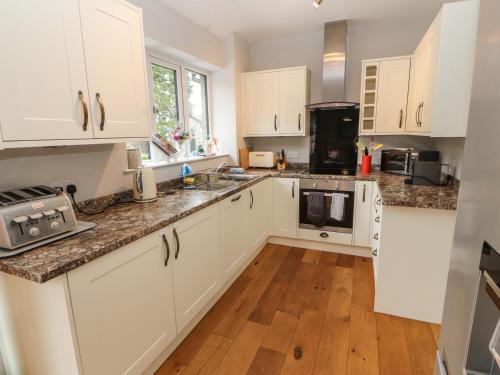 a kitchen with white cabinets and a wooden floor at Bishop Howe in Far Sawrey