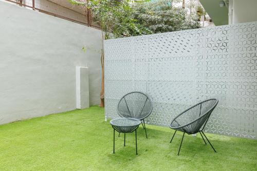 Snug studio apartment with pvt garden access I في أثينا: كرسيين جالسين على العشب بجانب جدار