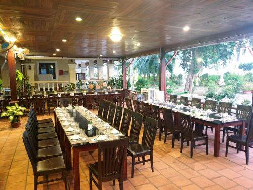 uma sala de jantar com mesas longas e cadeiras em Sài Gòn Côn Đảo Resort em Con Dao