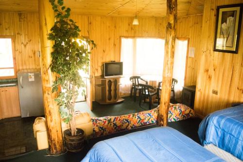 Habitación con 2 camas, TV y mesa. en Mae Joa Turismo - Cabañas & Camping Familiar en Ancud