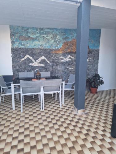 a dining room with a table and chairs and a wall at Villa Vista Norte in Porto Moniz