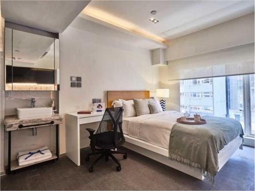 Schlafzimmer mit einem Bett, einem Schreibtisch und einem Waschbecken in der Unterkunft V Causeway Bay in Hongkong