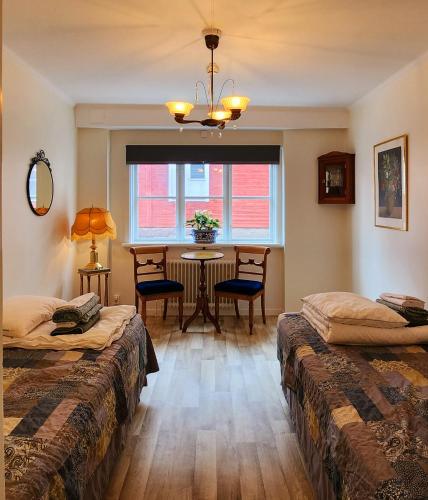 Cette chambre comprend 2 lits, une table et une fenêtre. dans l'établissement Vandrarhemmet Garvaren gamla stan Eksjö, à Eksjö