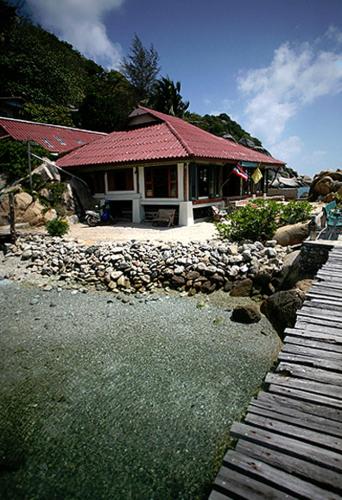 a house with a walkway next to a river at Lighthouse Bungalows in Haad Rin