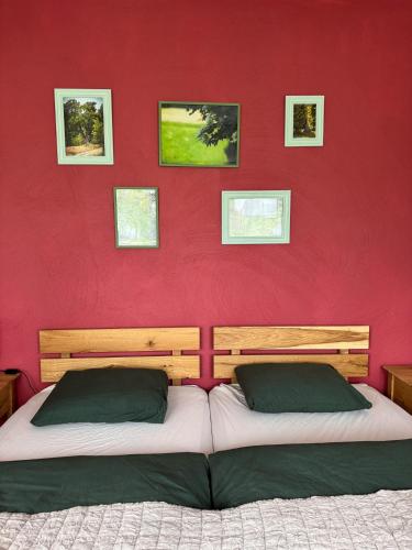 a bedroom with two beds with a red wall at Folwark Wierzchy in Wierzchy