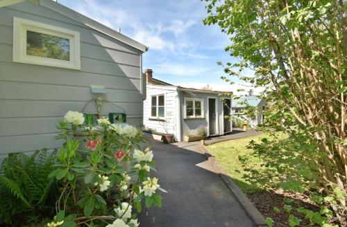 a tiny house with a garden next to a house at In Dunedin's Heart, Full House, Full Sun, Full Chill, Why Stay at a Hotel When You Can Afford an Entire House in Dunedin