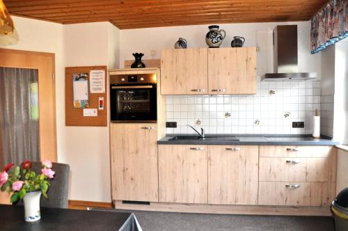 cocina con armarios de madera y nevera en Ferienwohnung Eudenbach, en Alsbach