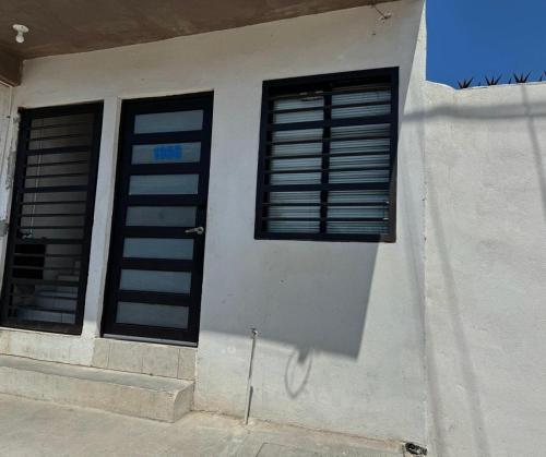 zwei Fenster auf der Seite eines weißen Gebäudes in der Unterkunft Acogedor depa cerca del Tec in Ciudad Victoria