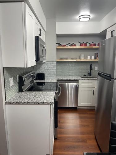 a kitchen with white cabinets and a stainless steel refrigerator at UMC Apartments in Oklahoma City