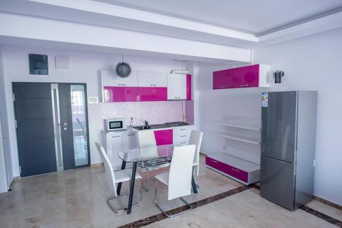 uma cozinha com mesa, cadeiras e armários cor-de-rosa em Sophia 2 & Moonlight Apartaments em Mamaia