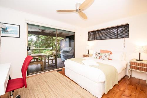 een slaapkamer met een wit bed en een rode stoel bij Blue Haven Pet Friendly Retreat in McCrae