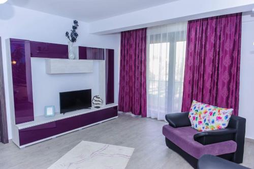 a living room with a purple couch and a fireplace at Sophia 2 & Moonlight Apartaments in Mamaia