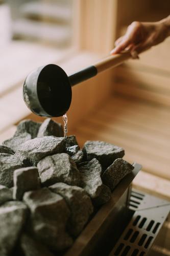 a person is pouring water from a pot on a pile of rocks at Modern 3-Bedroom Byron Bay Escape With Sauna in Byron Bay