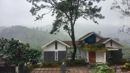 a house with a tree in front of it at Green Valley Holiday Home in Meppādi