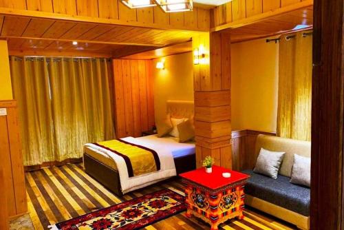 a bedroom with a bed and a couch and a table at Udaan Tashi Gakhil Resort in Lachung