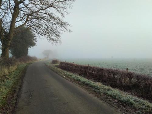 a dirt road next to the ocean on a foggy day at Feldhörn Comfortable holiday residence in Zetel