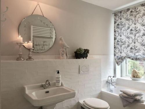 ein Badezimmer mit einem Waschbecken, einem WC und einem Spiegel in der Unterkunft Swan Heart Modern Retreat in Arnis