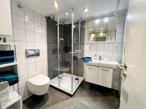 uma casa de banho com um chuveiro, um WC e um lavatório. em Porthole in the Seute Deern house em Juist