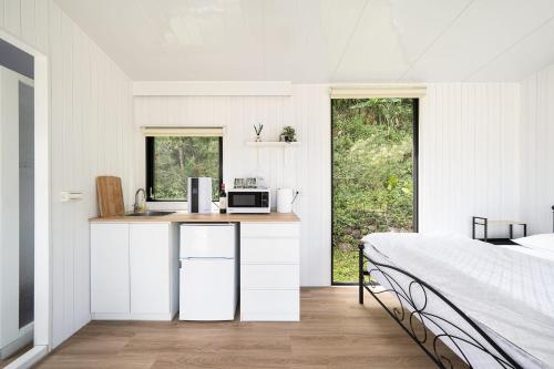 a white bedroom with a bed and a kitchen at Forest View Cottage 2 in Jiaoxi