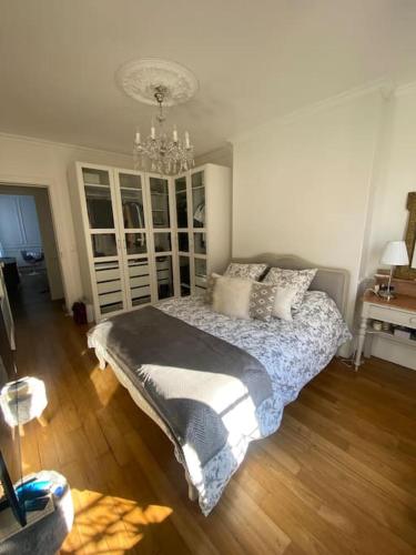 une chambre avec un lit et un lustre dans l'établissement Superbe appartement avec moulures et cheminé, à Clichy