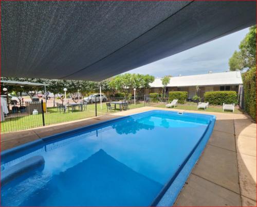 una grande piscina blu sotto una tettoia di Beagle Hotel a Katherine